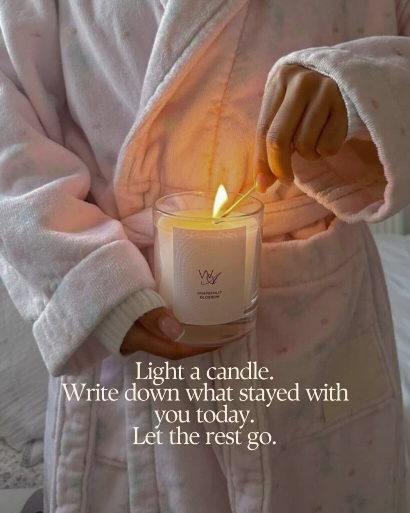 A warm, moody evening scene with a lit candle, an open journal, and a cup of tea on a nightstand in soft, dark lighting.