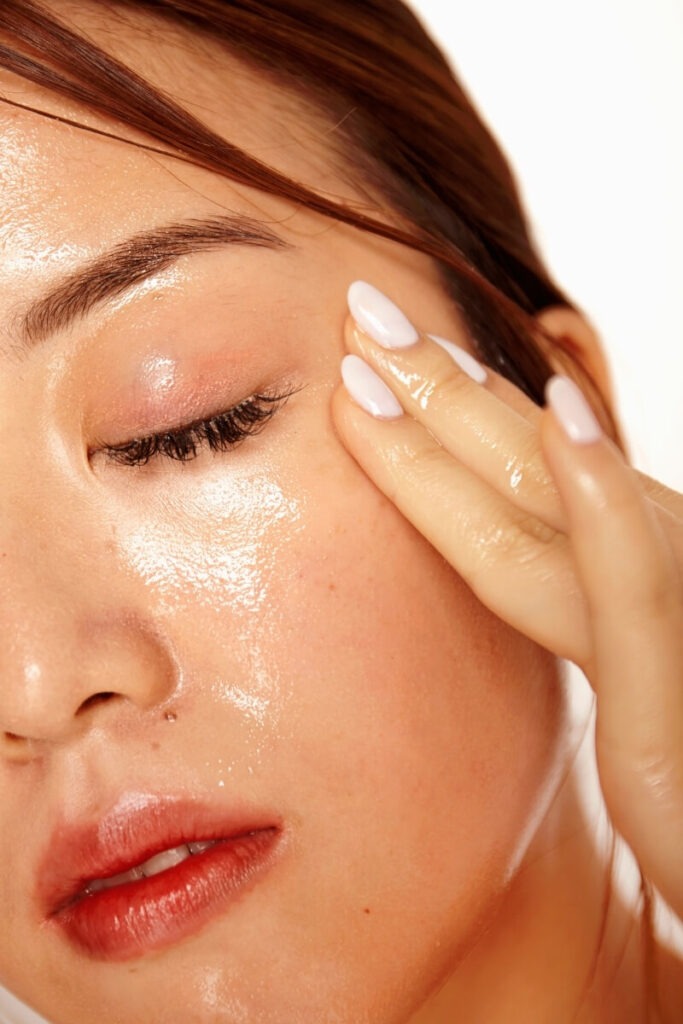 Person applying oil cleanser to remove makeup and sunscreen from their face