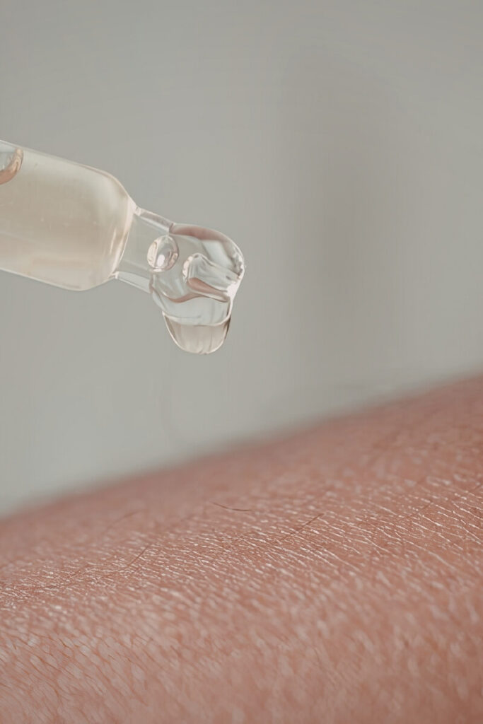 Dropper applying hydrating serum onto clear glowing skin