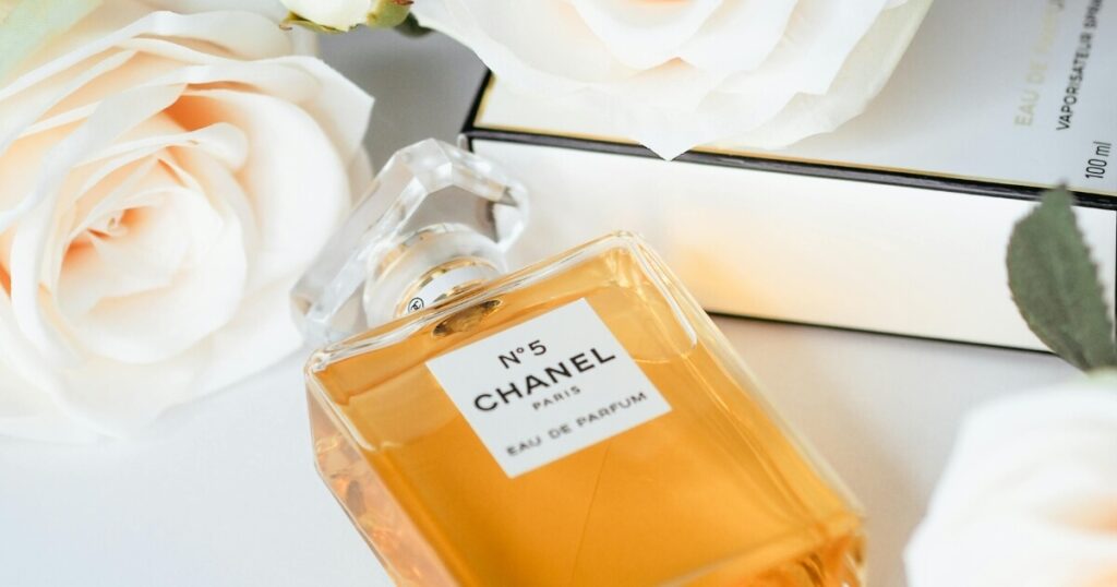 A Chanel perfume bottle placed among fresh pink roses, creating a luxurious and elegant composition.