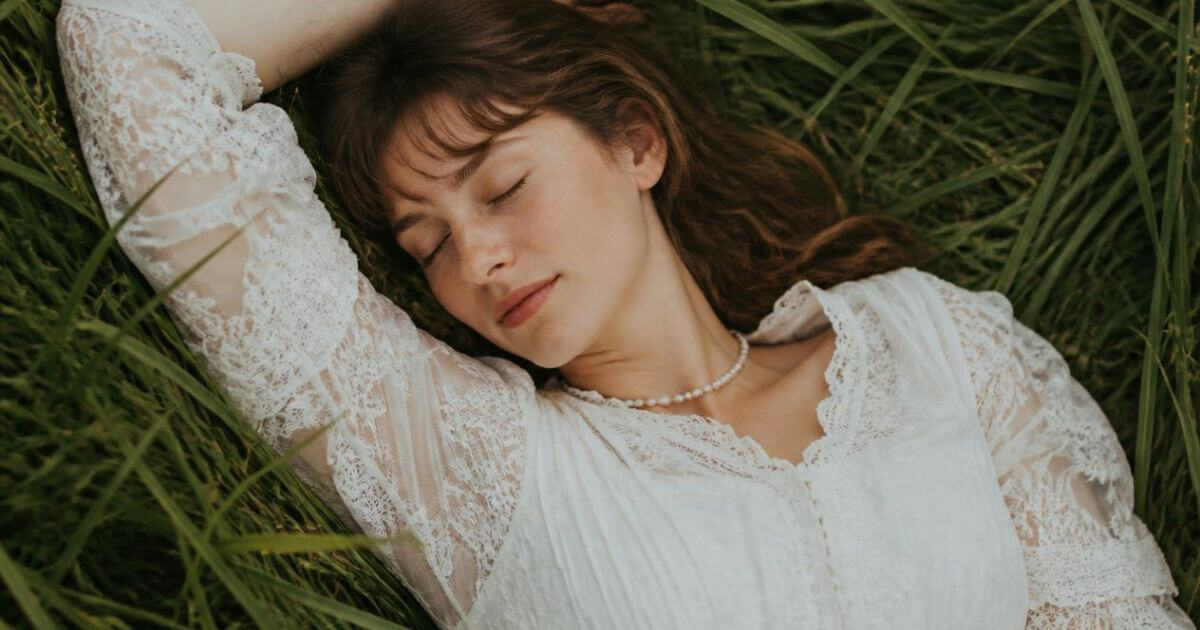 Woman lying peacefully in a wildflower meadow, soft feminine era mood