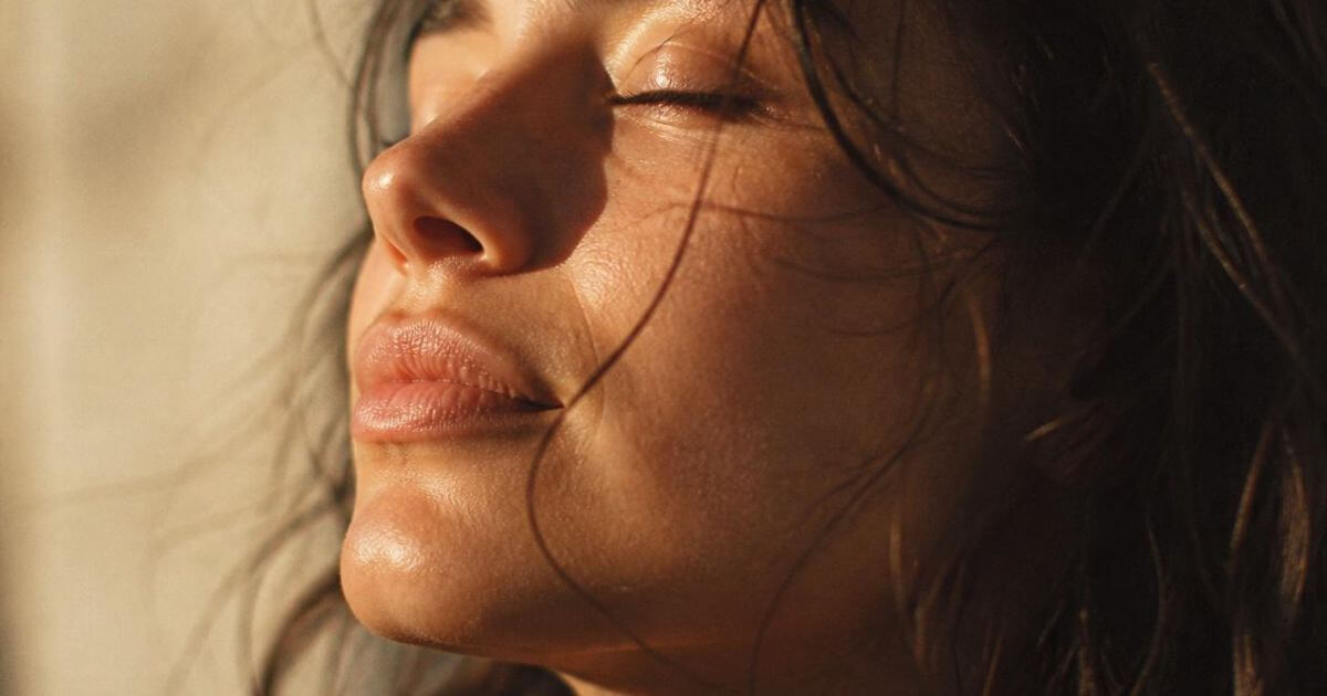Close up portrait of woman with closed eyes in warm sunlight