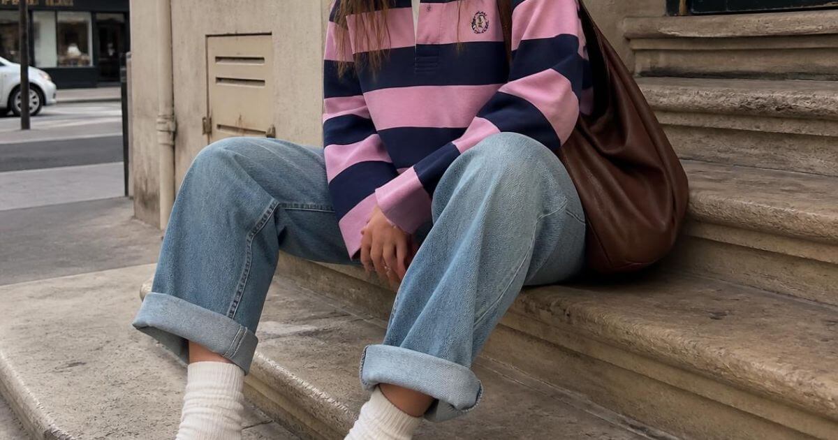 Woman in a striped sweater and light wash jeans sitting on stone steps