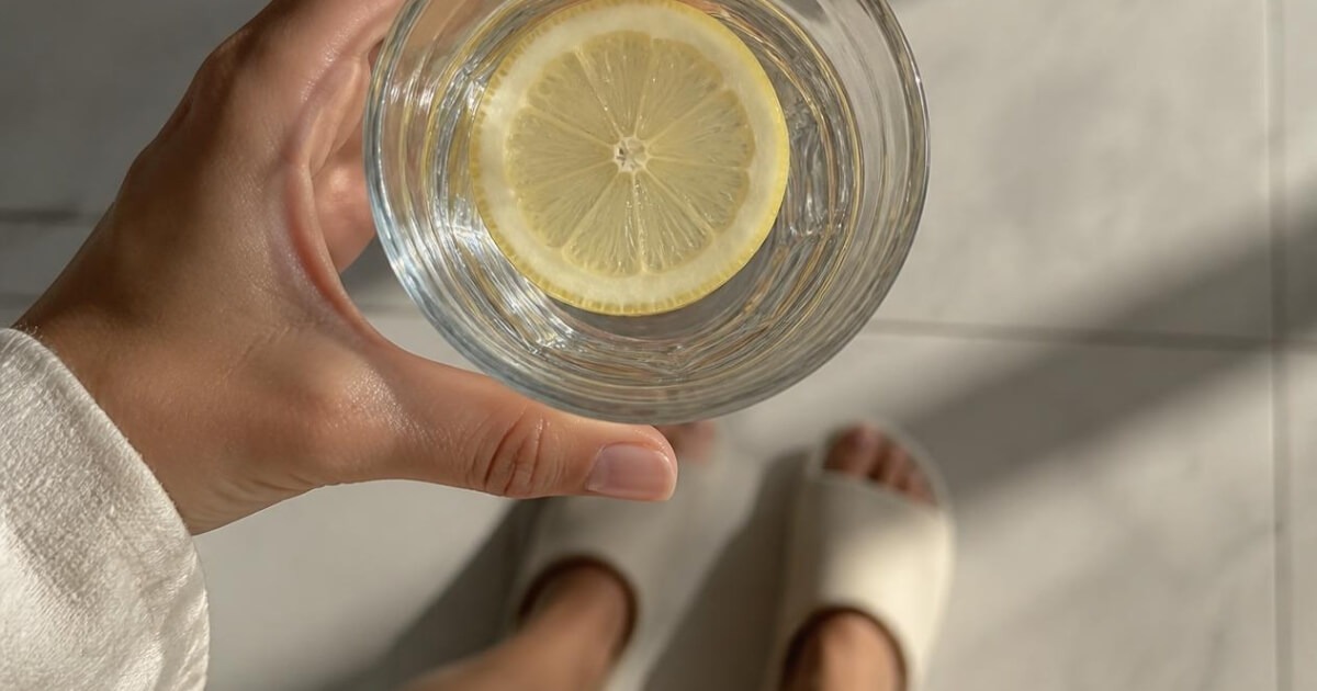 Woman drinking water in soft morning light as part of her morning routine
