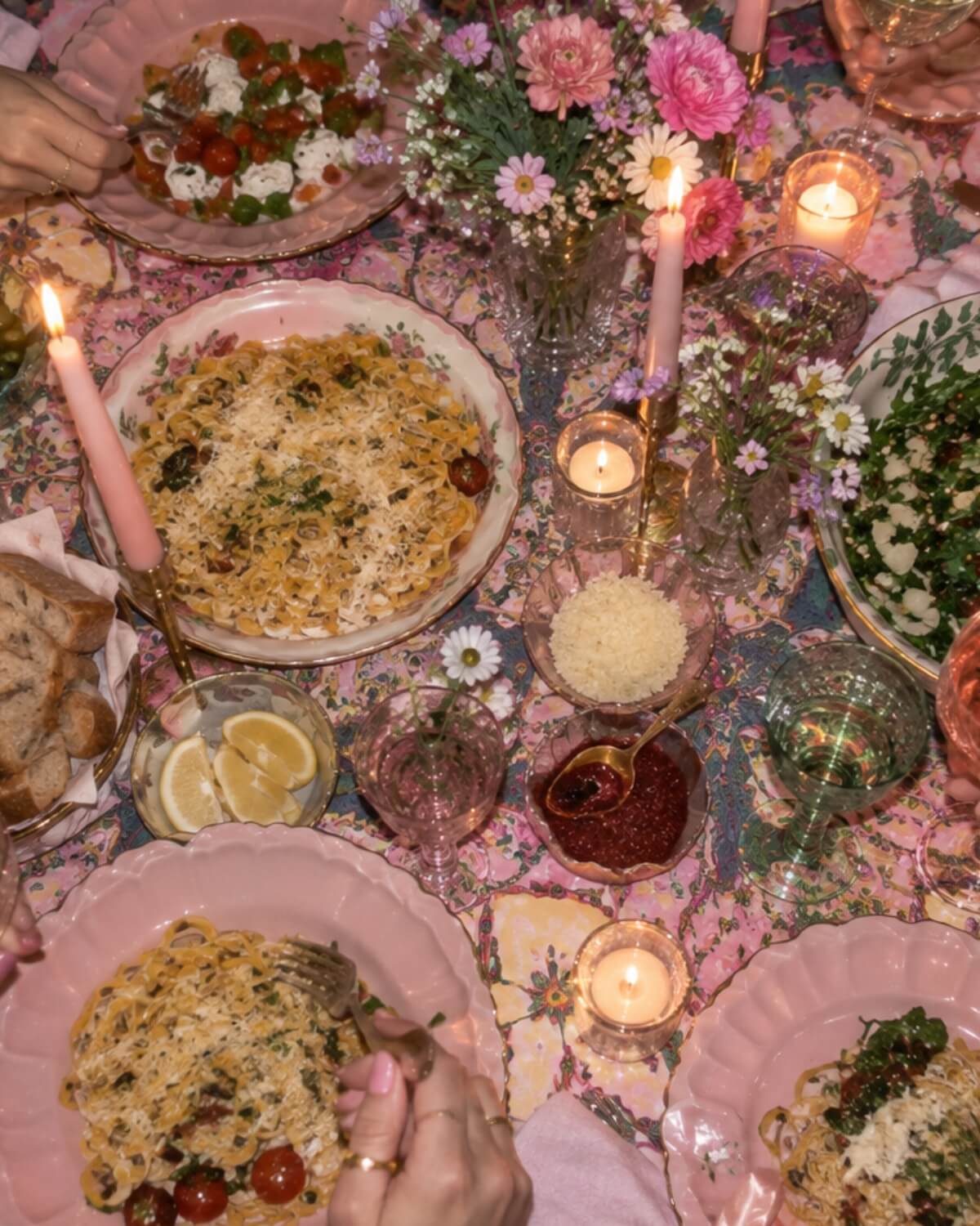 Colorful girls' dinner party table with pink plates, patterned tablecloth, candles and flowers, a lived whimsy themed dinner