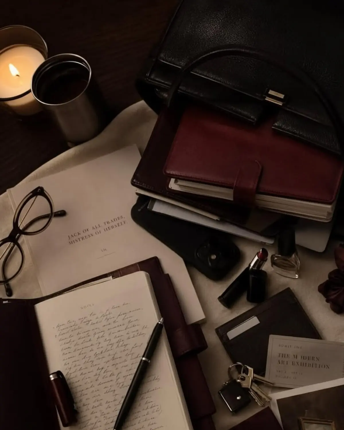 Open handwritten journal with a fountain pen, a burgundy leather planner and a candle on a dark desk, a quiet shadow work practice