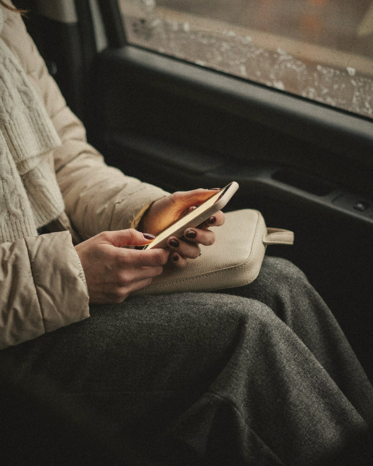 Hands with burgundy nails typing a message on a phone in the back of a taxi after an event, following up to build social connection